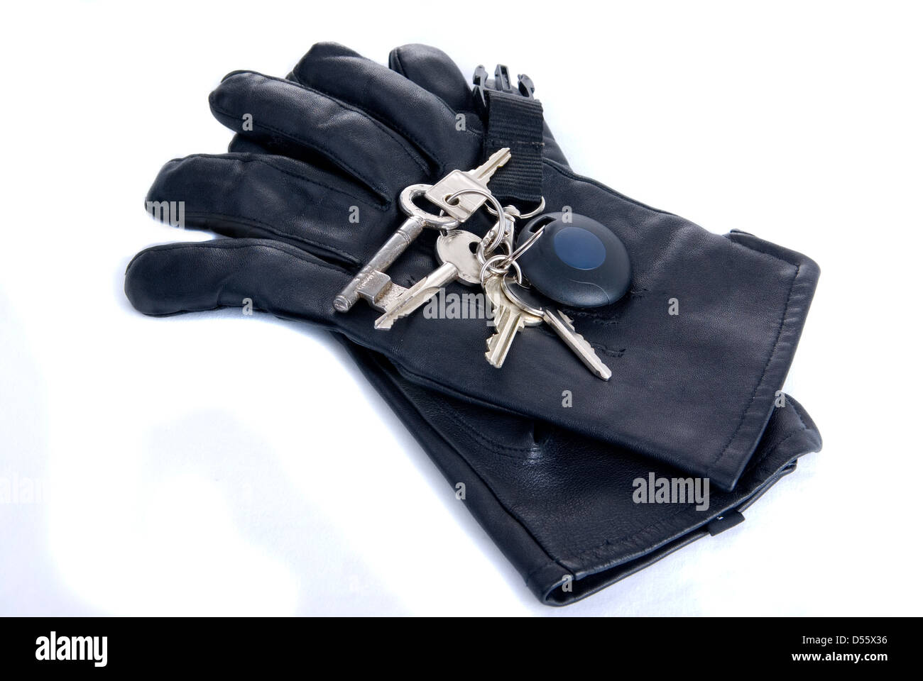 Gruppe von Schlüsseln auf schwarze Lederhandschuhe, isoliert auf weiss Stockfoto
