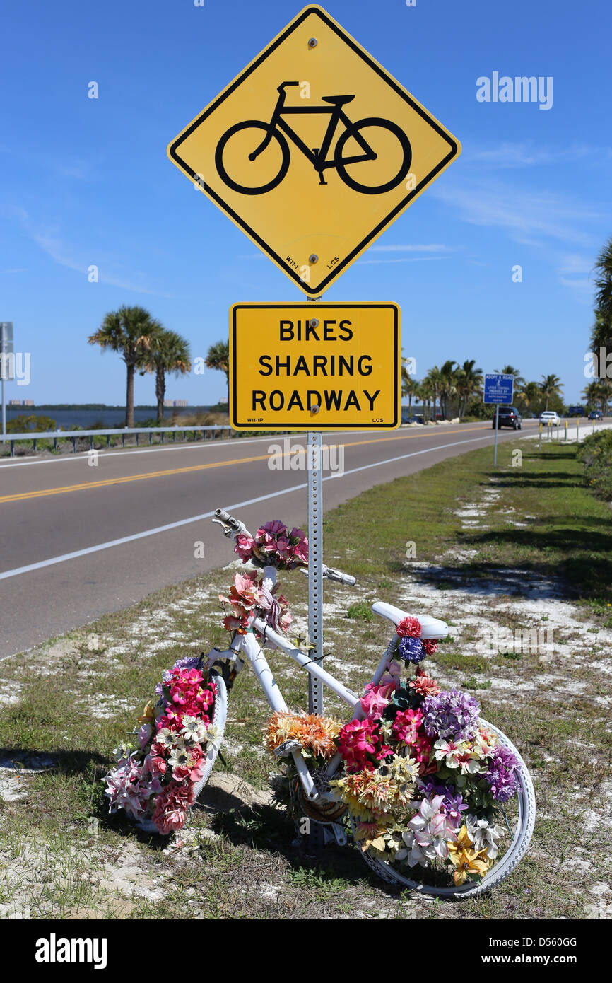 ein Autobahn-Schild auf Sanibel Island Florida USA sagen Vorsicht Fahrräder teilen Fahrbahn mit einem echten Motorrad mit Blumen geschmückt Stockfoto