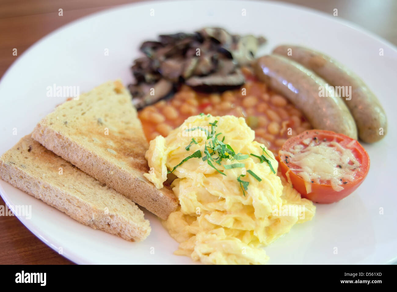 Rührei Würstchen mit Toast Brot gebacken, sautierten Pilzen Bohnen und Tomaten mit geschmolzenem Käse Frühstück Stockfoto