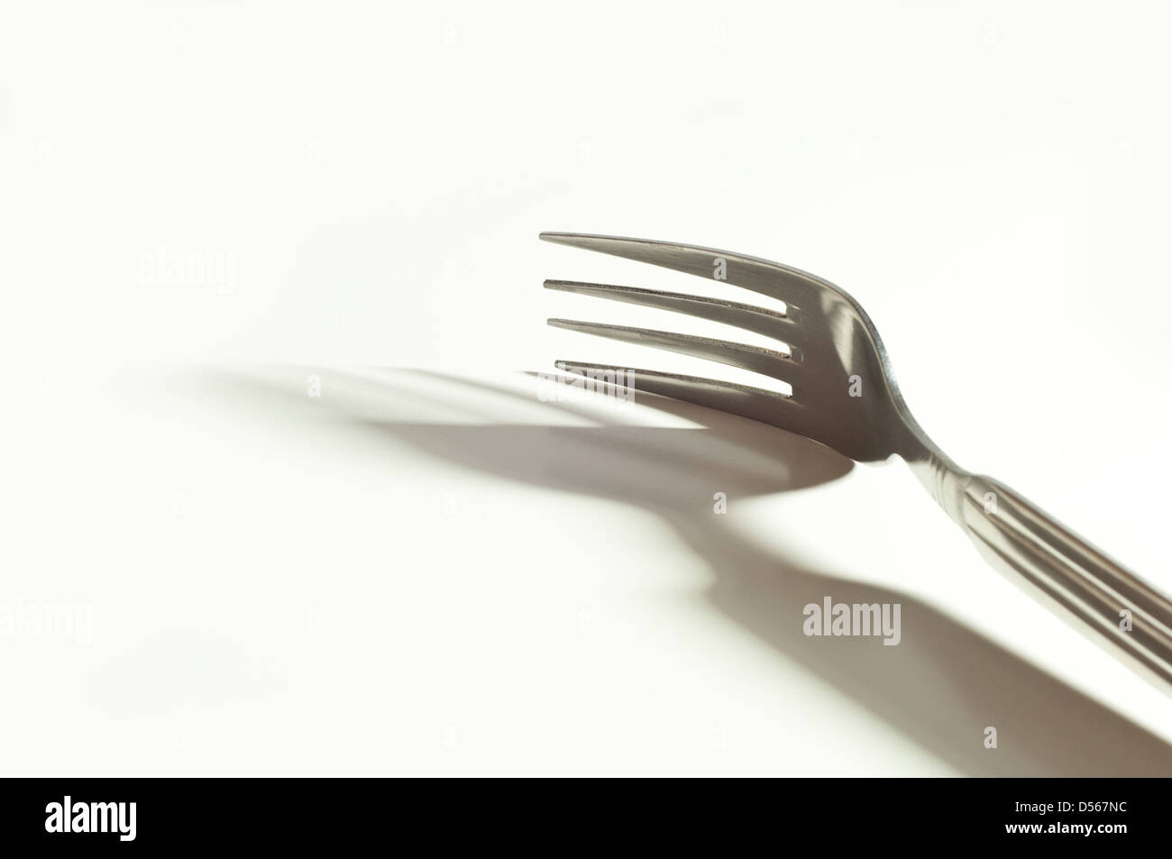 metallische Gabel und ihr Schatten auf dem weißen Hintergrund Stockfoto