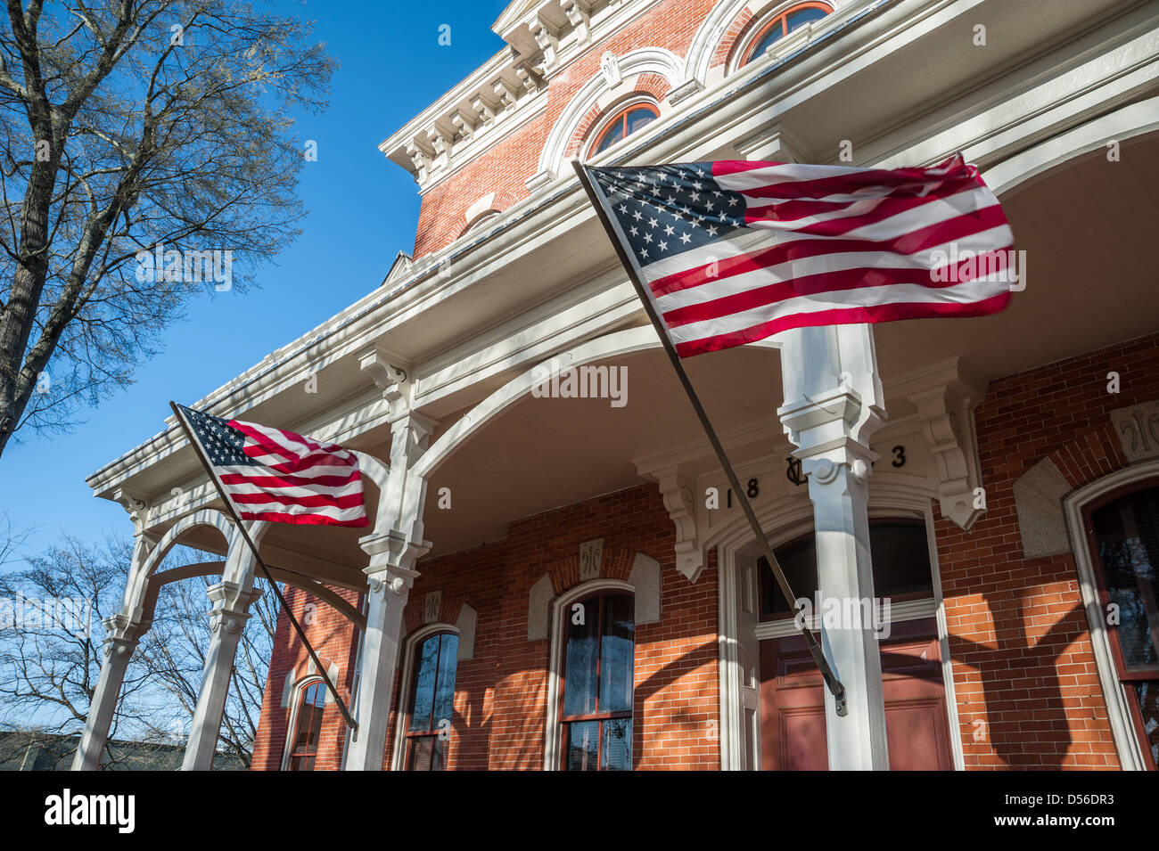 Amerikanische Flaggen wehten von der Veranda-Beiträge von der historischen Walton County Courthouse auf dem Platz in der Innenstadt von Monroe, Georgia. Stockfoto