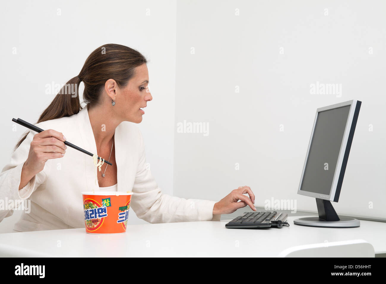 Reife Geschäftsfrau instant-Nudeln zu essen, am Schreibtisch Stockfoto