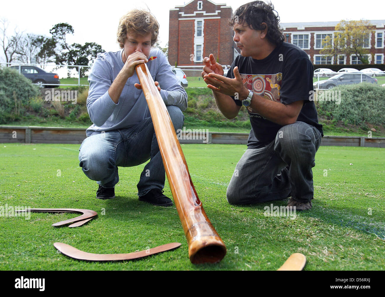 Aborigine Ron Murray (R) lehrt deutsche Formel1 Fahrer Seabstian Vettel von Red Bull ein Didgeridoo spielen in Melbourne, Australien, 24. März 2010. Zum Formel 1 Grand Prix von Australien statt findet auf Albert Park Circuit am 28. März 2010. Foto: JENS Büttner Stockfoto