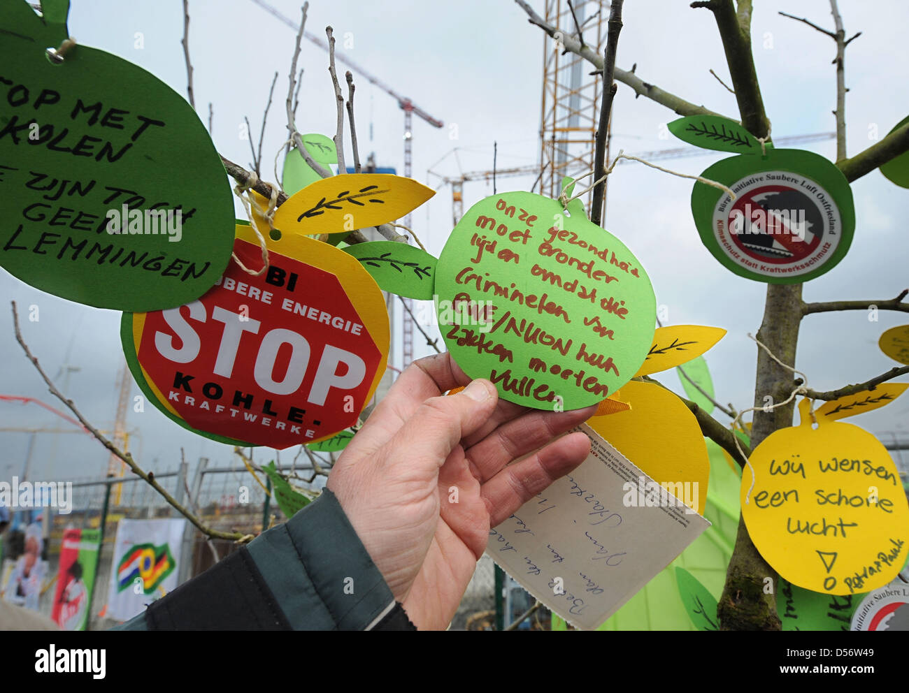 Umweltschützer binden ihre Wünsche für die Umgebung, um einen frisch gepflanzten Apfelbaum in der Nähe einer Baustelle des Energieversorgers RWE ein Kohlekraftwerk in Eemshaven, Niederlande, 27. März 2010. Rund 100 deutsche und niederländische Umweltschützer beteiligte sich an der Protest-Veranstaltung; die Initiative fand im Rahmen einer Demonstration gegen den Bau von Kohle- Stockfoto