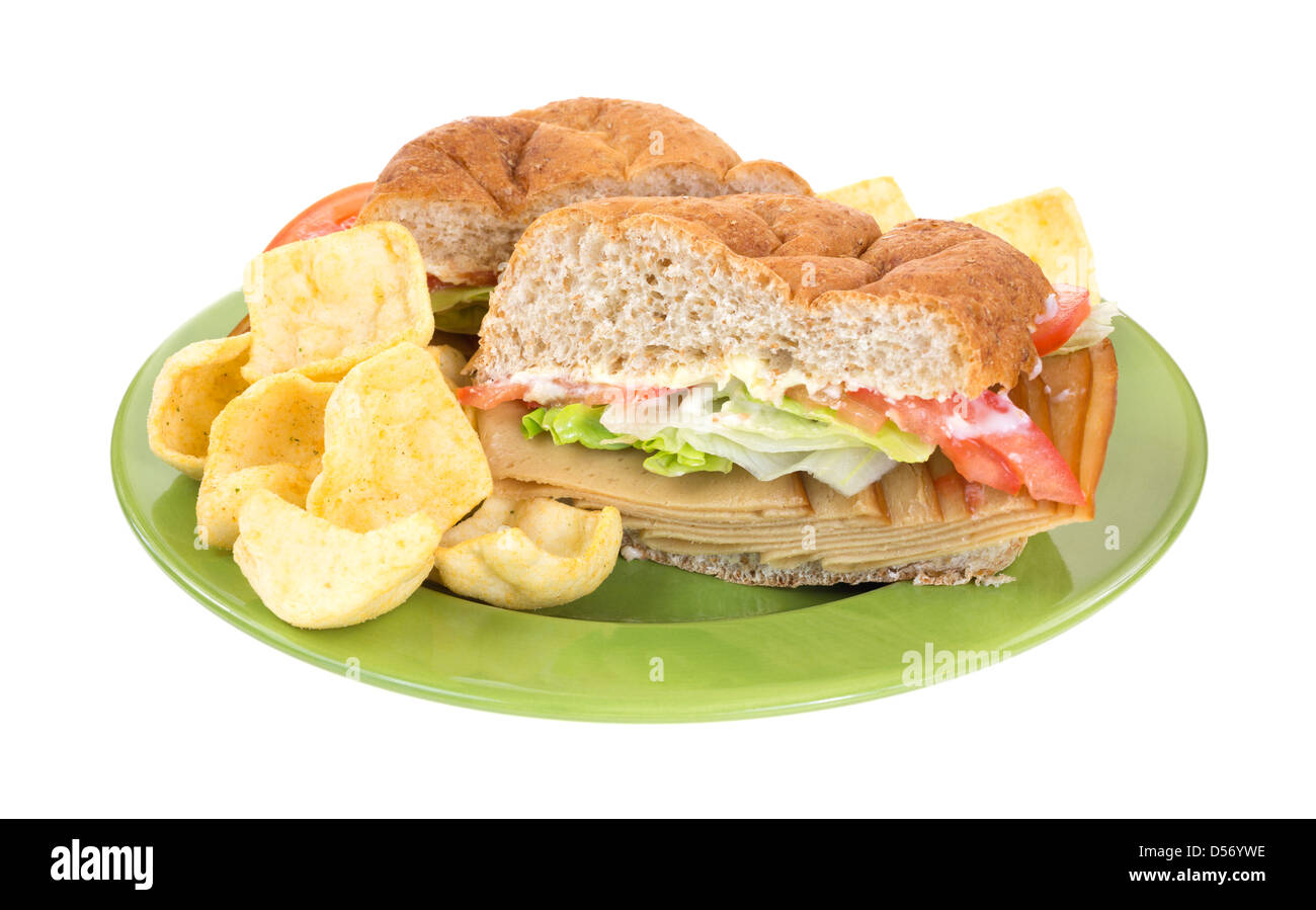 Eine sperrige Weizen Roll Türkei Tofu-Sandwich mit Salat Tomaten und Mayonnaise und Chips auf eine grüne Platte. Stockfoto