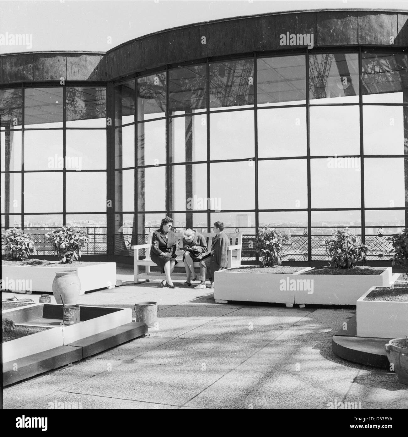 1950, Paris, Frankreich, meine Damen sitzen auf einer Bank in der open-air auf der ersten Ebene des berühmten französischen Denkmal, der Eiffelturm, ein schmiedeeisernes Gitter Turm auf den Champs de Mars. Große Fenster kann im Bild ermöglicht einen Blick über die Stadt gesehen werden. Stockfoto