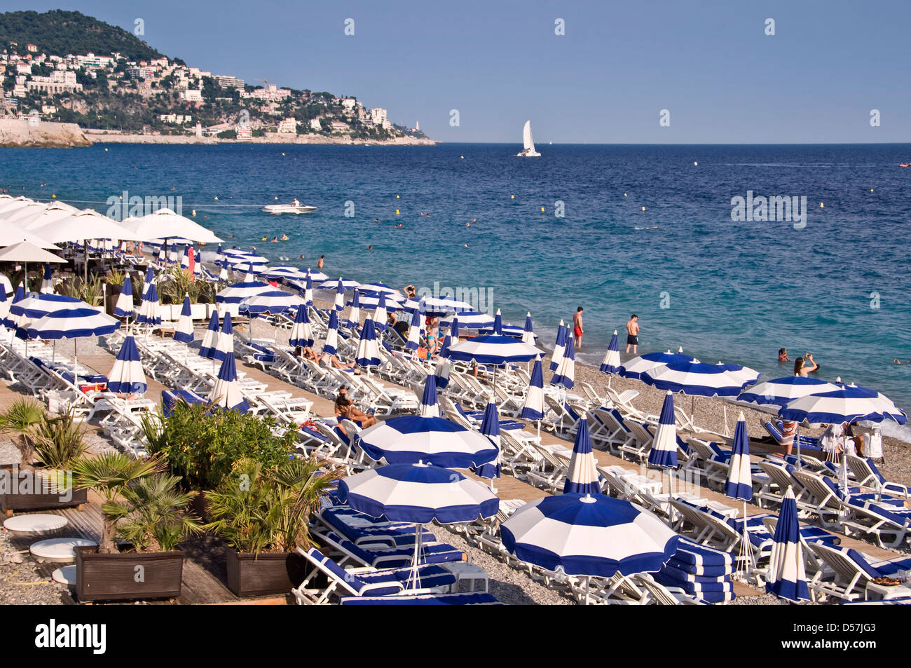 Privatstrand mit blauen Sonnenschirmen, Meer im Hintergrund Ansicht von oben - Nizza, Frankreich Stockfoto