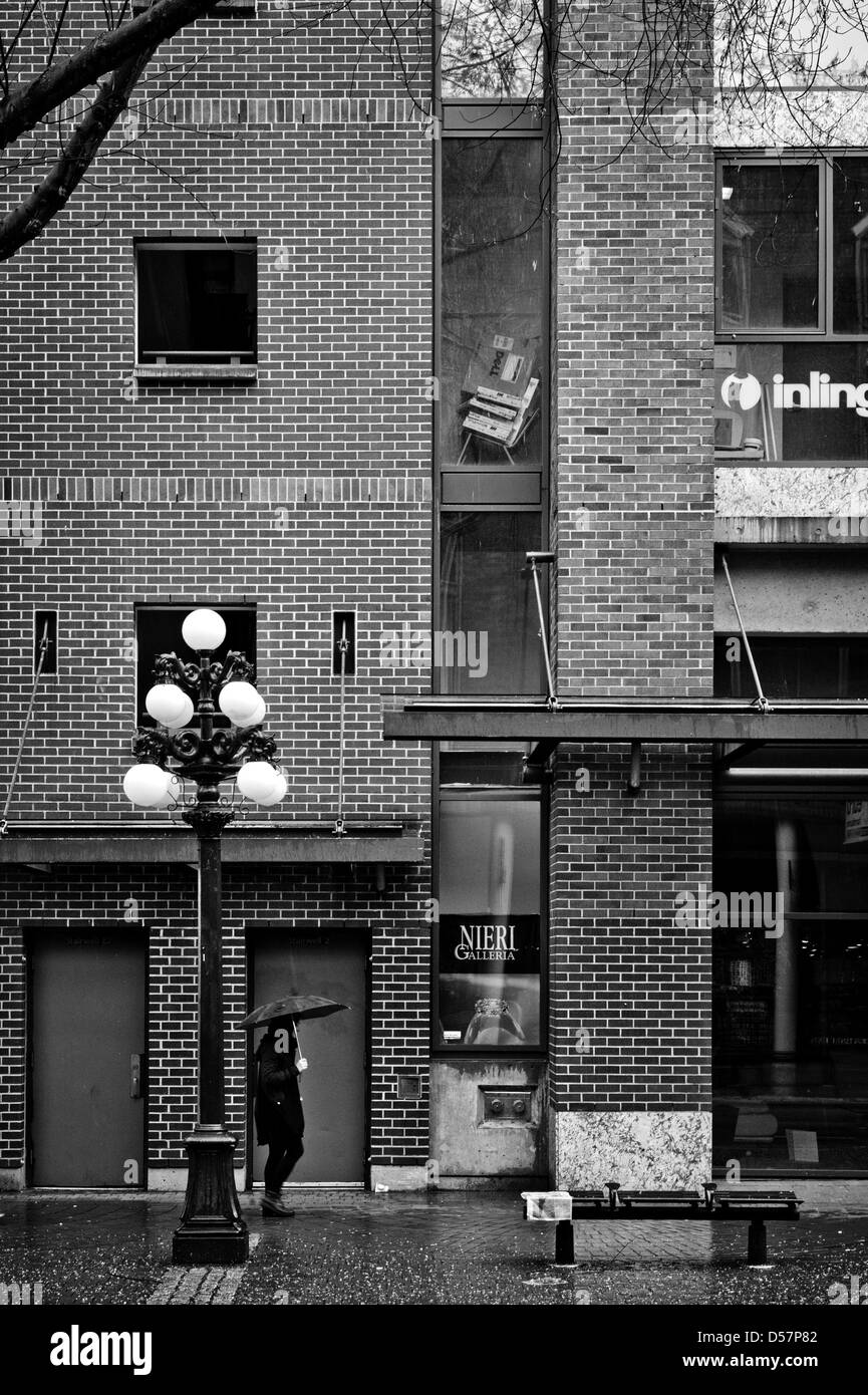 Eine Dame zu Fuß im Regen auf Water Street in der Innenstadt von Vancouver BC Stockfoto