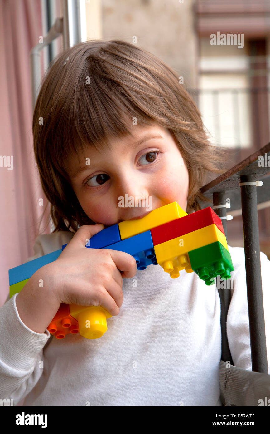 Gesunder vier Jahre alter Junge mit Pistole gemacht aus Legosteinen glauben machen. Stockfoto