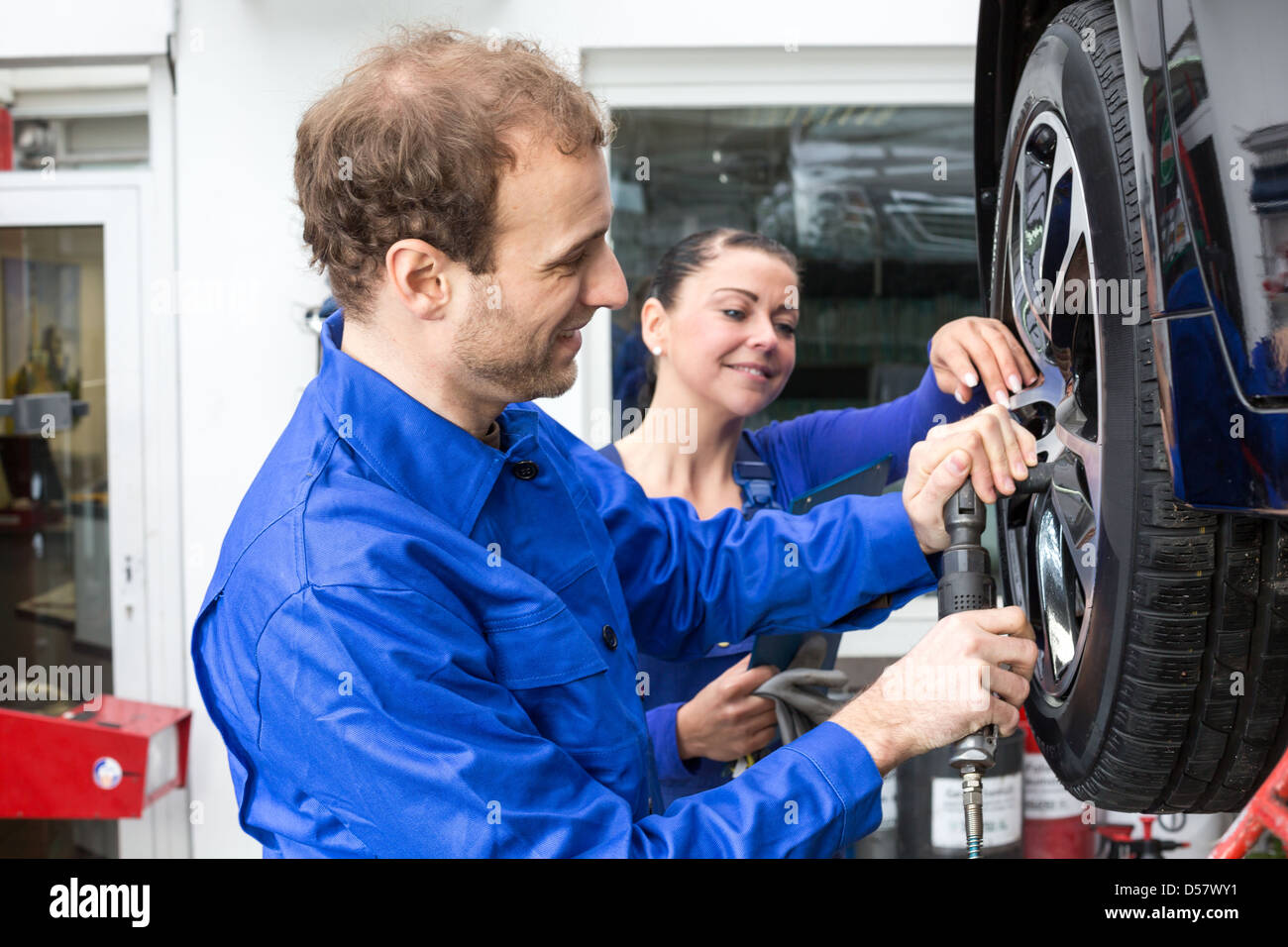 Zwei Mechaniker Radwechsel auf einem Auto stehend auf eine hydraulische Rampe Stockfoto