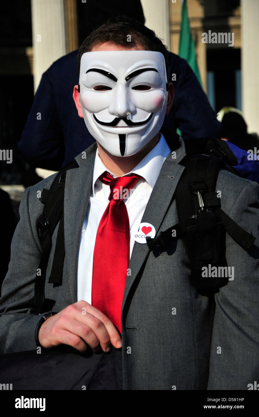 Ein Mann mit einer roten Krawatte mit einem anonymen Maske bei einer Kundgebung auf dem Trafalgar Square, London, UK Stockfoto