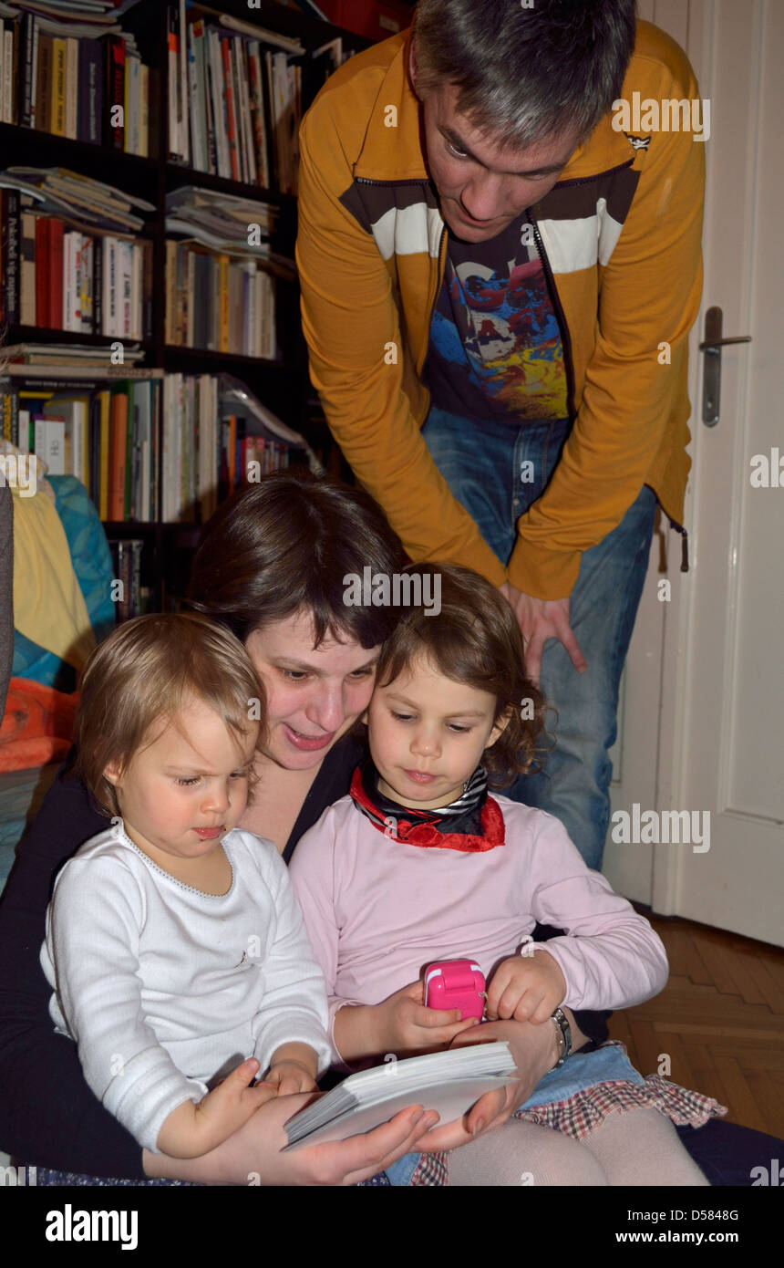 Kleine Mädchen und Eltern beobachten klassischen Papier-Fotos Stockfoto