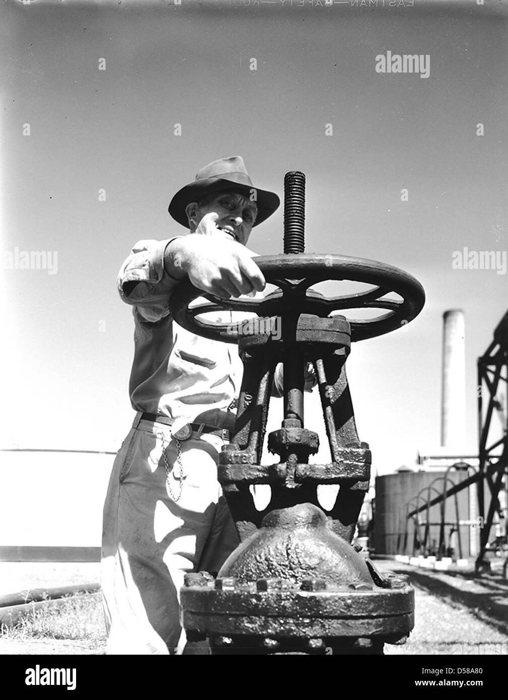 Dieses Bild zeigt einen Arbeiter in Texaco in Texas, der ein Ventil in einer Erdölanlage bedient. Das Foto zeigt die industrielle Arbeit in der Ölindustrie und erfasst die technischen Aspekte der Erdölverarbeitung. Stockfoto