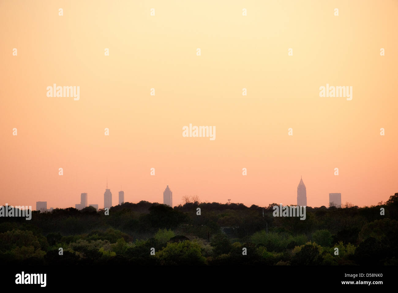 Die Skyline von Atlanta gebadet in das orange Leuchten des Sonnenuntergangs über dem bewaldeten Gelände von Stone Mountain Park gesehen. Stockfoto