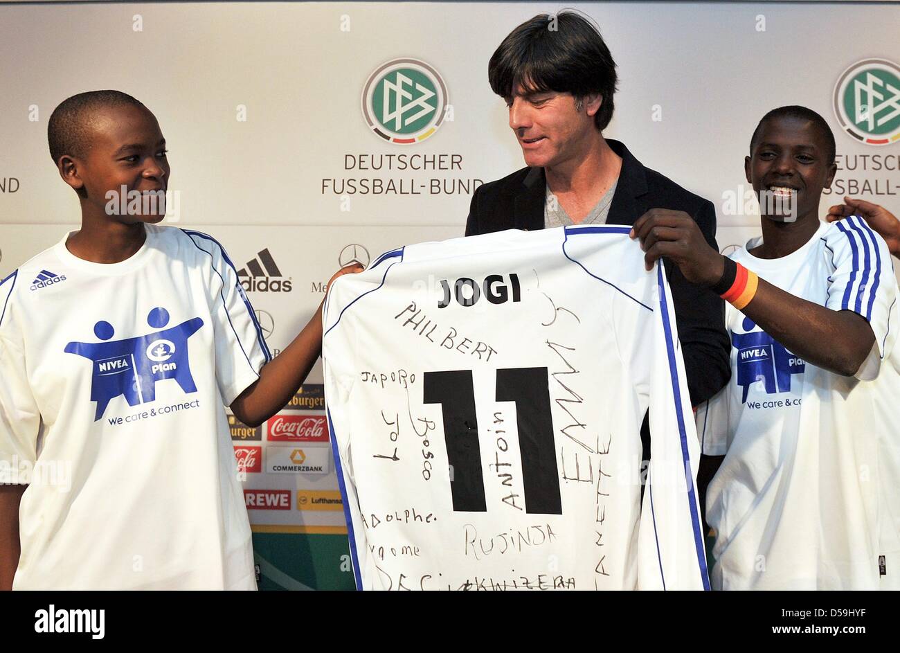 Zwei ruandische Kinder des Unterprojekts Plan International präsentieren deutsche Headcoach Joachim Loew (C) eine Trikot im Rahmen einer Pressekonferenz der deutschen Mannschaft im Velmore Grand Hotel in Erasmia bei Pretoria, 25. Juni 2010. Joachim Loew unterstützt ein Projekt mit 16 Kindern. Foto: Bernd Weißbrod Dpa - verweisen wir auf http://dpaq.de/FIFA-WM2010-TC +++(c) Dpa - Bildfunk +++ Stockfoto