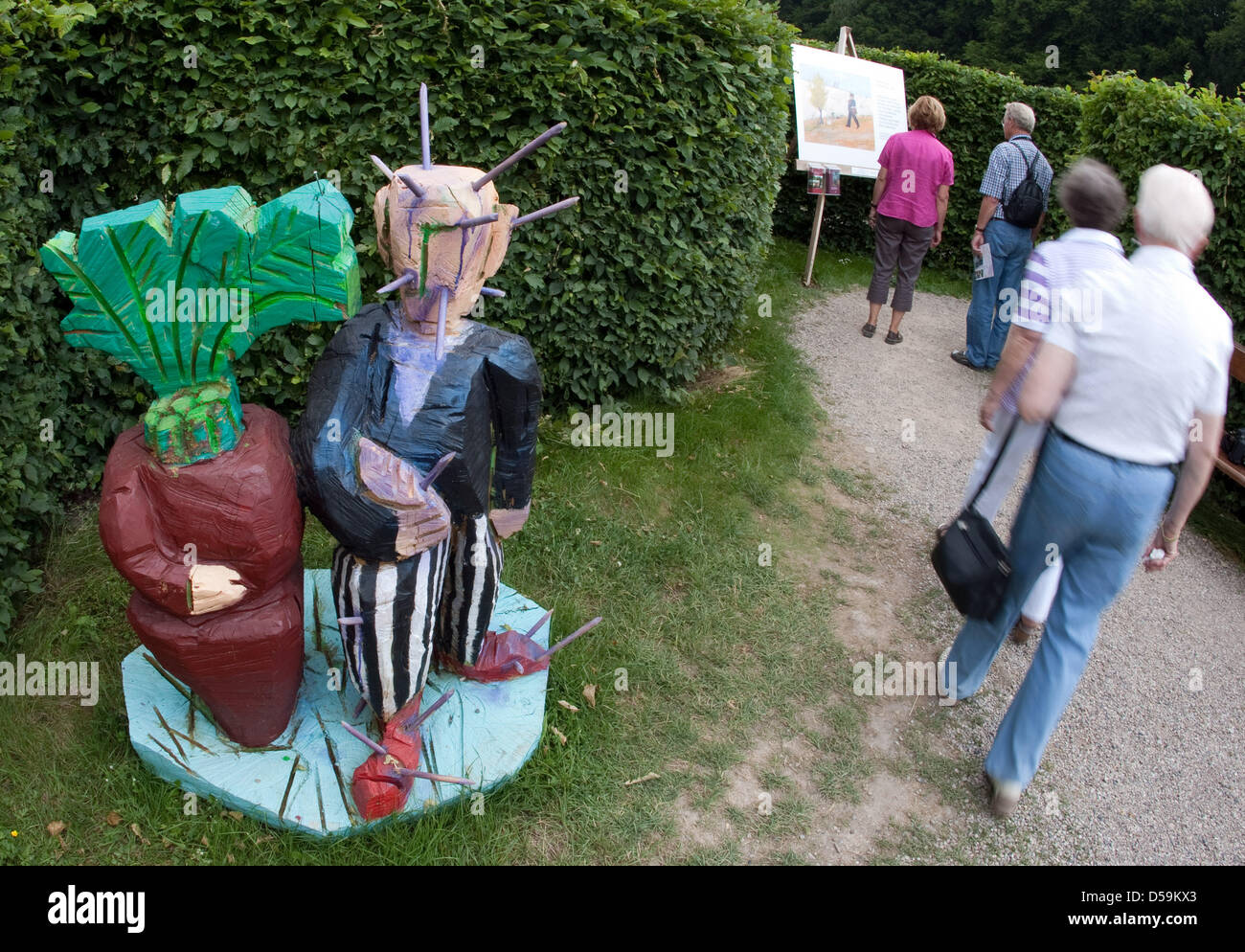 Ausstellungsbesucher pass durch eine Skulptur des Künstlers Werner Kavermann auf der State Horticultural Show Schloss Ippenburg in Bad Essen, Deutschland, 25. Juni 2010. Die Skulptur zeigt die Zeichen Herr Kaktus und Frau Palm aus dem Trickfilm "Pit und Peggs". Bis 1936 war der Film ein Projekt von Felix Nussbaum, ein jüdischer Maler, der 1944 in Auschwitz ermordet wurde. Der Film wurde nie Stockfoto