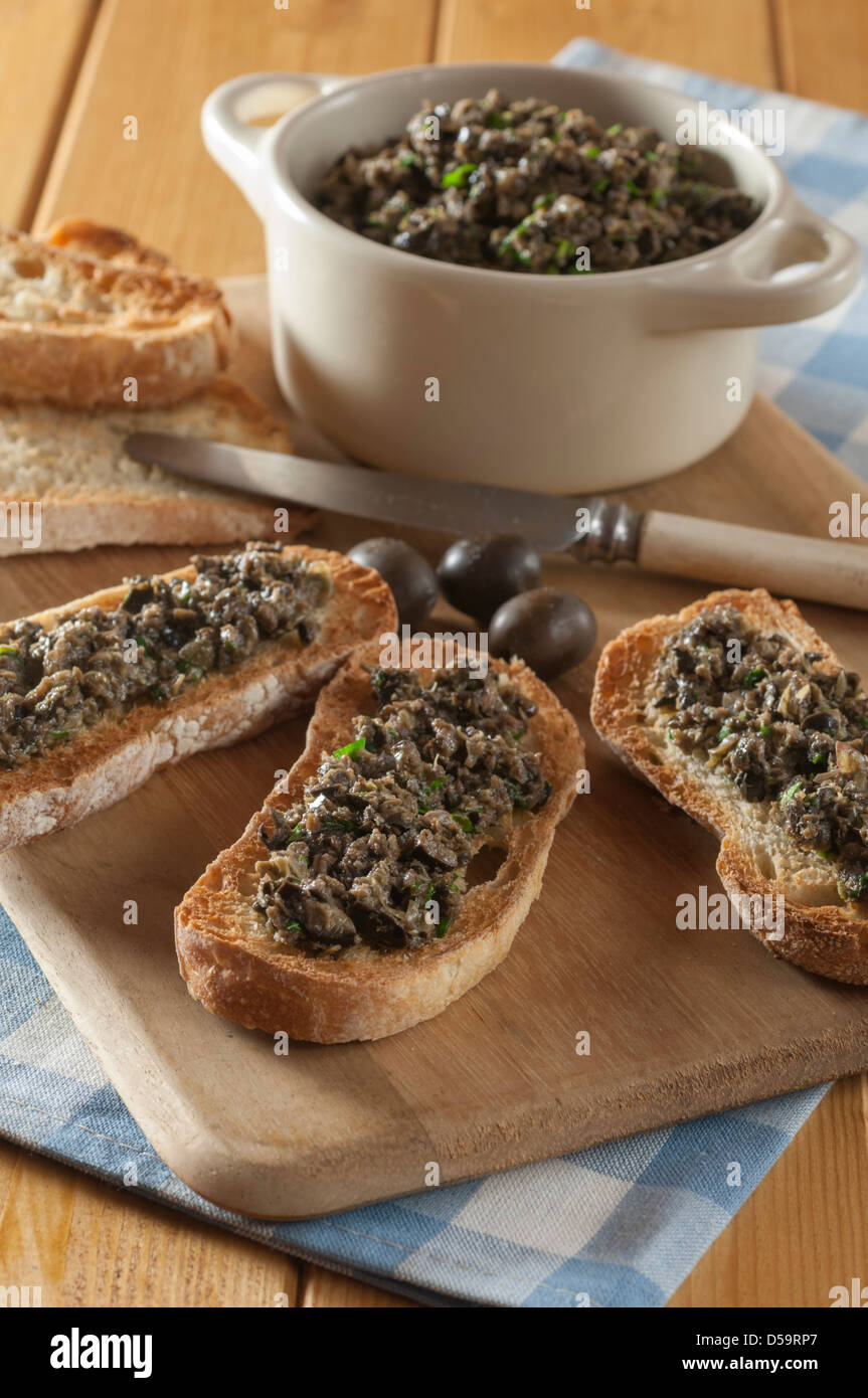 Schwarze Oliven Tapenade auf geröstetem Baguette Stockfoto