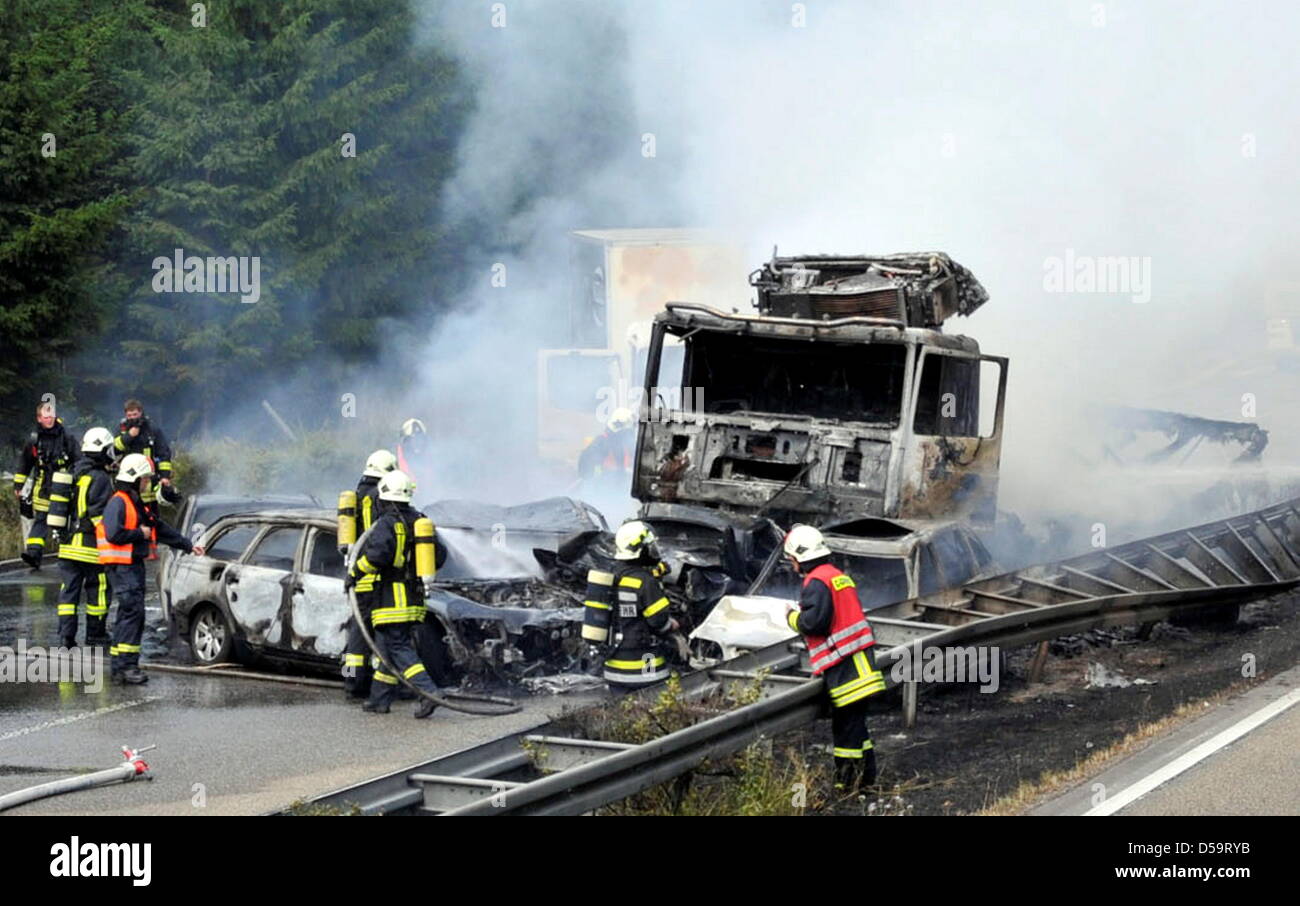 Feuerwehr löscht brennende Fahrzeuge auf der Autobahn 31 bei Dorsten, Deutschland, 2. Juli 2010. Eine mehrere Auto-Pile-Up zwei Menschen das Leben gekostet. Abgesehen von einem Warnschild, hatte ein LKW in das hintere Ende des Stau bei fast voller Geschwindigkeit schlug der Polizei gemeldet. Die Autos Ahed des LKW waren in oder übereinander geschoben. Zwei Personen verbrannte in ihren Fahrzeugen. A Stockfoto