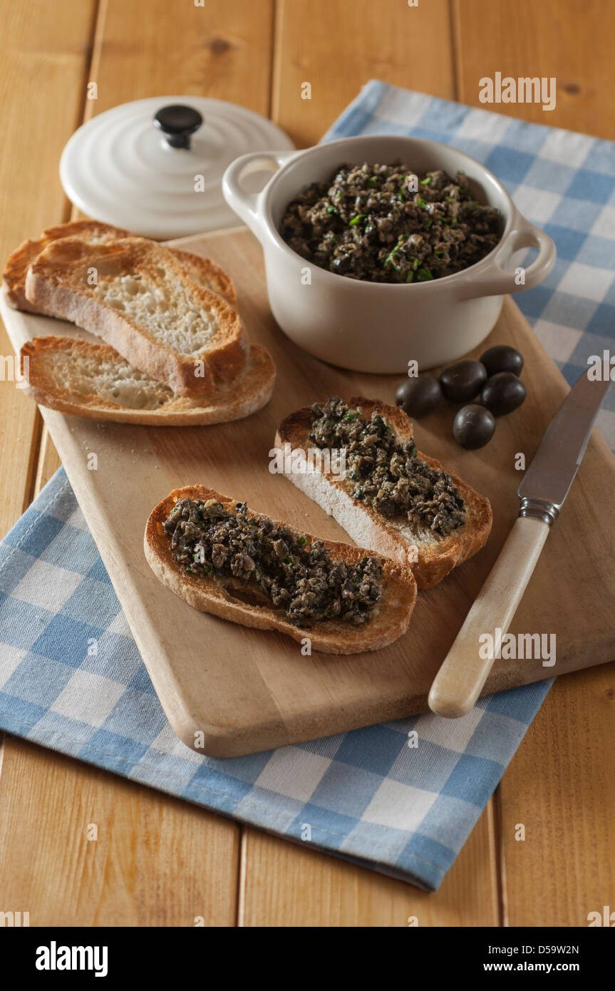 Schwarze Oliven Tapenade auf geröstetem Baguette Stockfoto