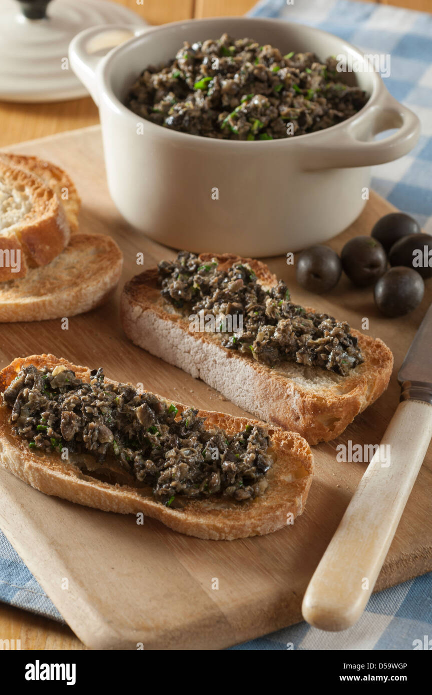 Schwarze Oliven Tapenade auf geröstetem Baguette Stockfoto