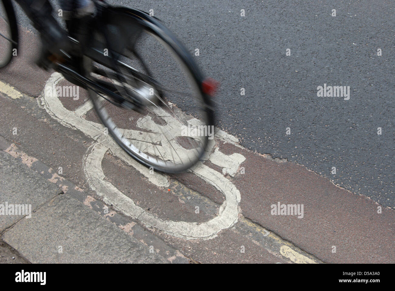 Radfahrer in ein Radweg vorbei ein Fahrrad Bild teilweise verdeckt durch eine neue Straße-Abdeckung Stockfoto