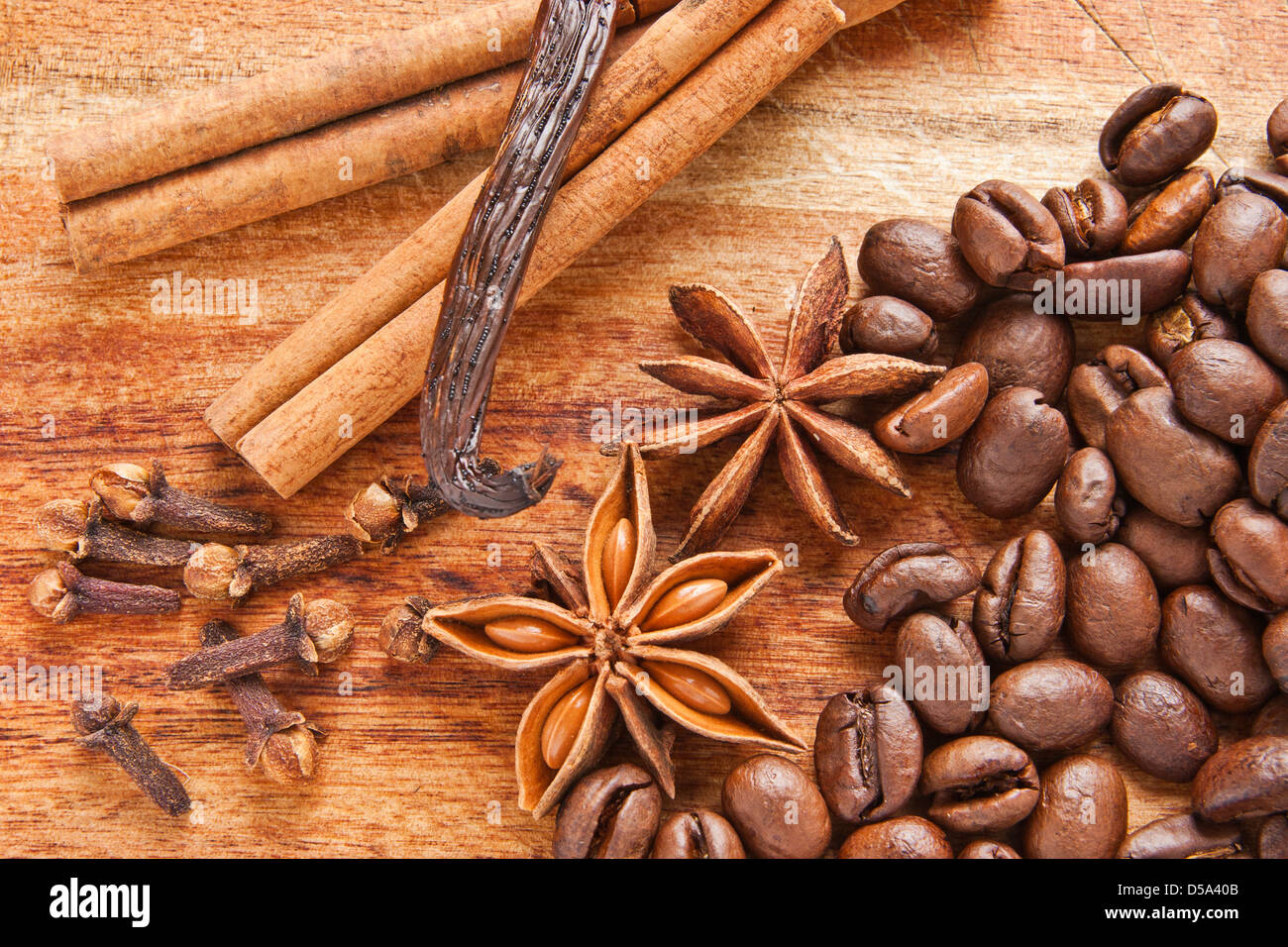 Kaffeebohnen, Sternanis, Vanilleschote, Nelken und Zimtrinde auf dem Holz Schreibtisch Stockfoto