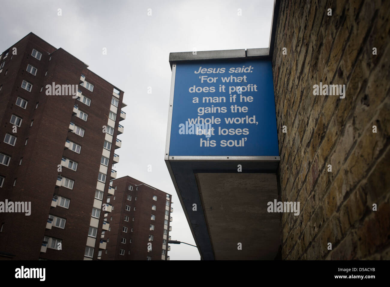 "Jesus sagte" biblische Zitate auf einer Stadtkirche und düsteren Hintergrund Hochhäuser im Londoner Stadtteil Southwark. Einheimische in diesen trostlosen South London Straßen können durch die Worte aus der christlichen Schriften, erhoben werden, tröstet den unruhigen mit Nachrichten der Menschheit aus der Bibel, vielleicht Führung Londoner eingesperrt in deprimierenden 1960er Jahre Hochhaus Hochhäuser, Häuser für die Armen und die Besitzlosen. Stockfoto