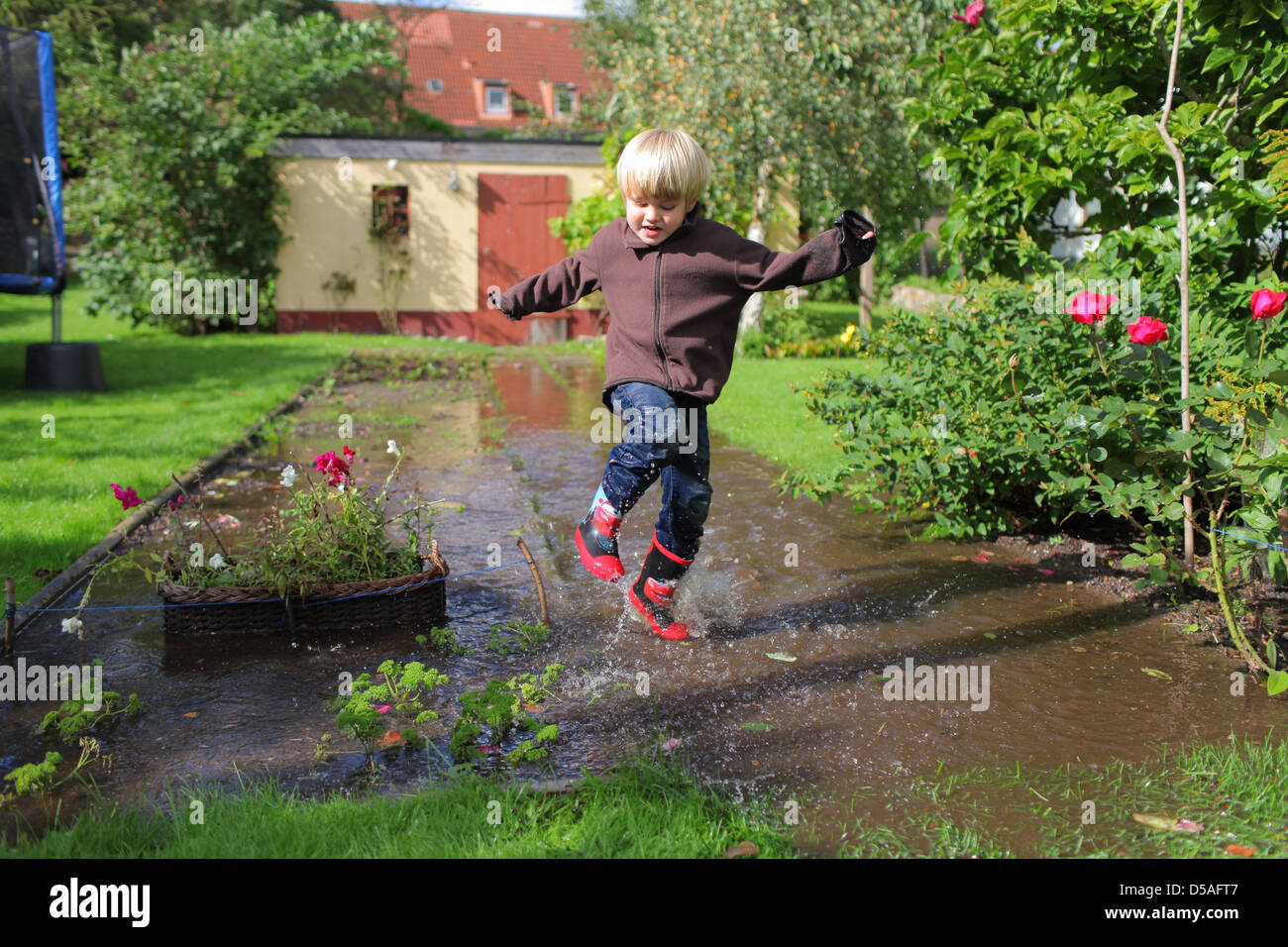 Handewitt, Deutschland, eine junge läuft in Latex Stiefel durch eine über überflutete Garten Stockfoto