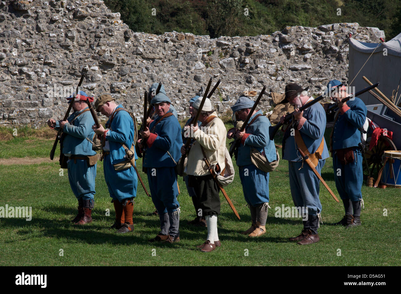 Eine Gruppe von englischen Bürgerkrieg reenactors in die Uniformen der royalistischen Musketiere laden sie ihre Waffen zum Brennen bereit. Corfe Castle, Dorset, England, UK. Stockfoto