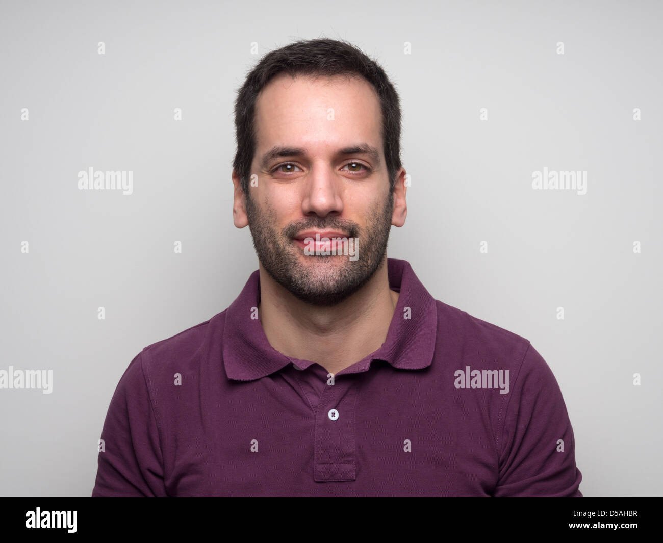 Porträt eines 3-tägigen bärtigen jungen Mannes trägt ein lila Poloshirt Stockfoto