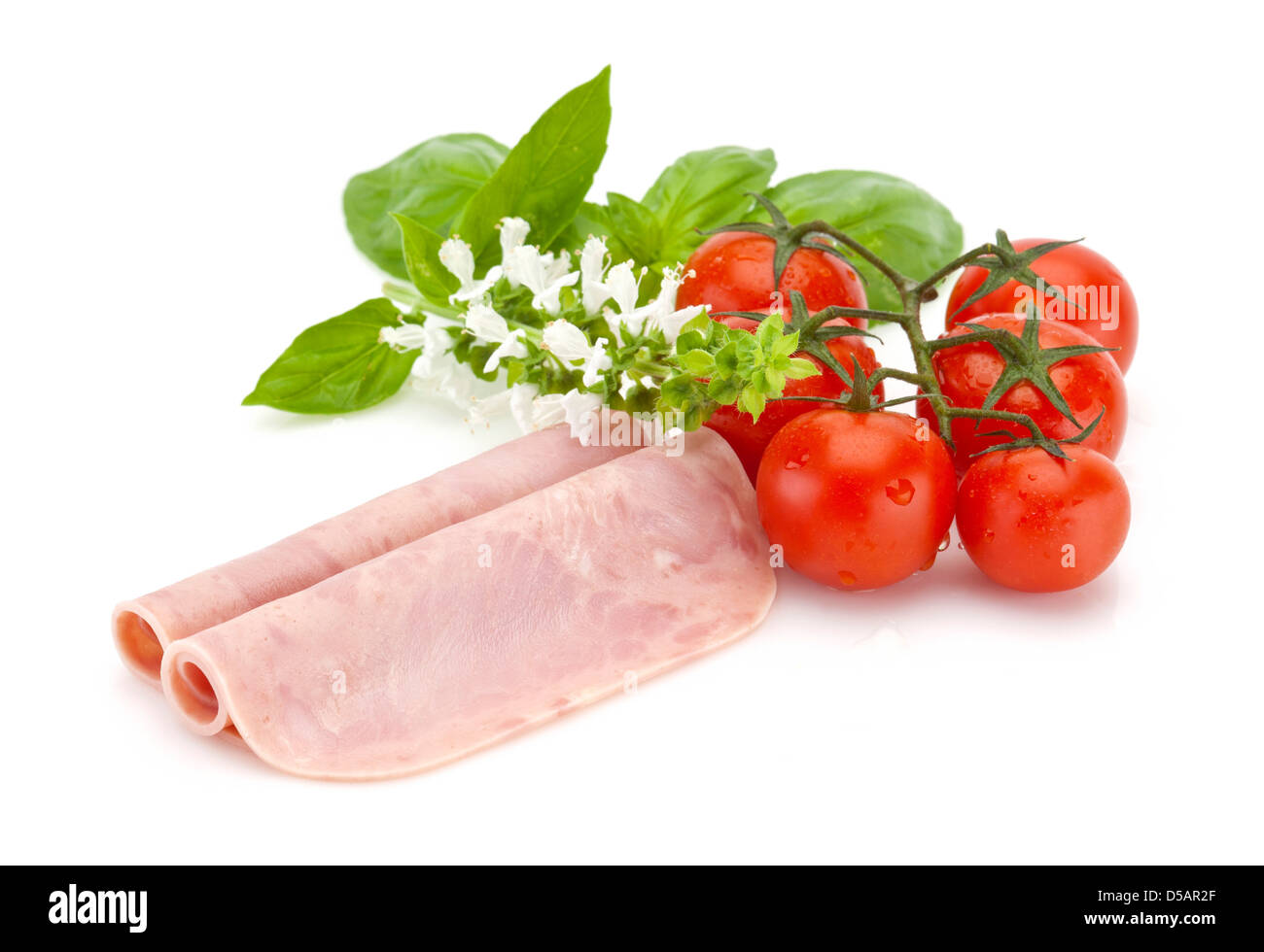 zwei Scheiben Kochschinken mit Cherry-Tomaten und Basilikum Stockfoto