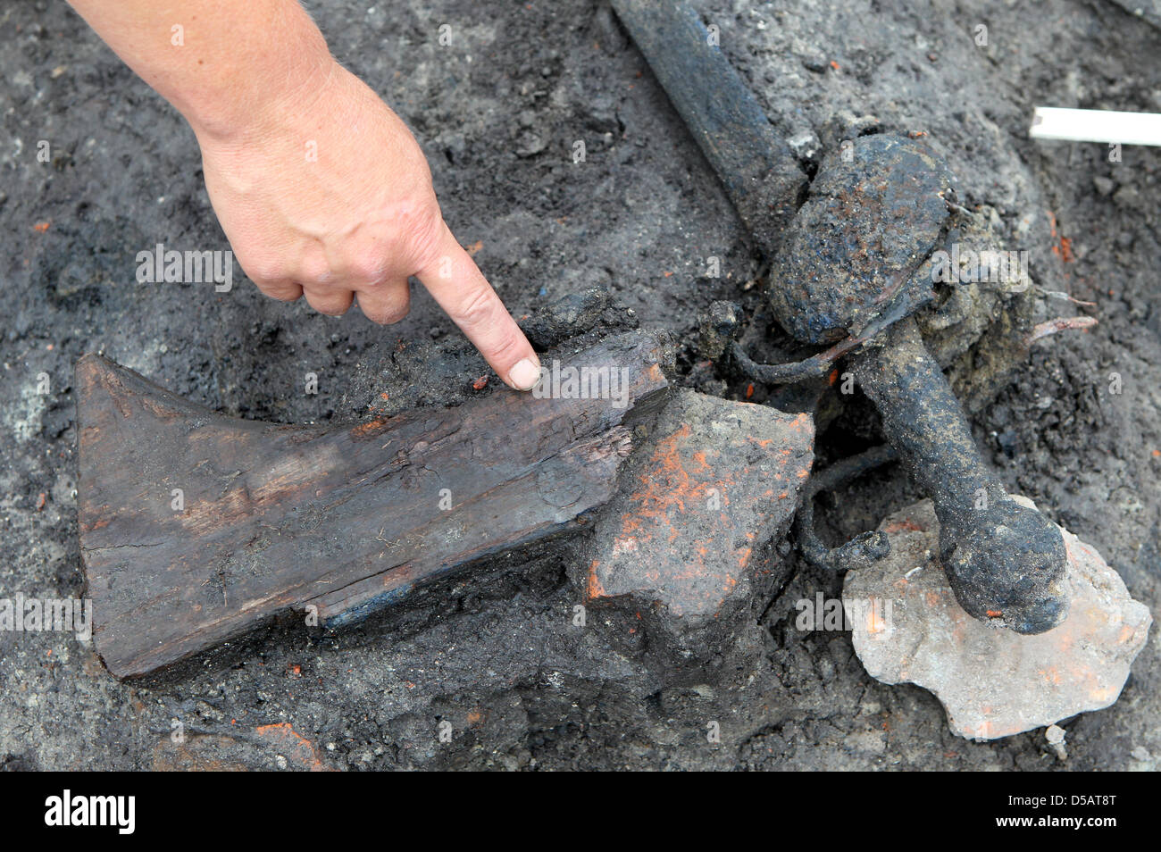 Ein Archäologe weist auf den Bestand an einer Muskete liegen neben Überreste von zwei Soldaten, die im Dreißigjährigen Krieg in Stralsund, Deutschland, 13. Juli 2010 gestorben. Es ist sehr wahrscheinlich, dass die beiden Landsquenets Wallensteins Truppen gehörten, die während einer Belagerung im Jahre 1628 überrannt wurden. Die Tatsache, dass Waffen gefunden werden ist eine außergewöhnliche Sache als in der Regel die getöteten Soldaten Sachen und Stockfoto