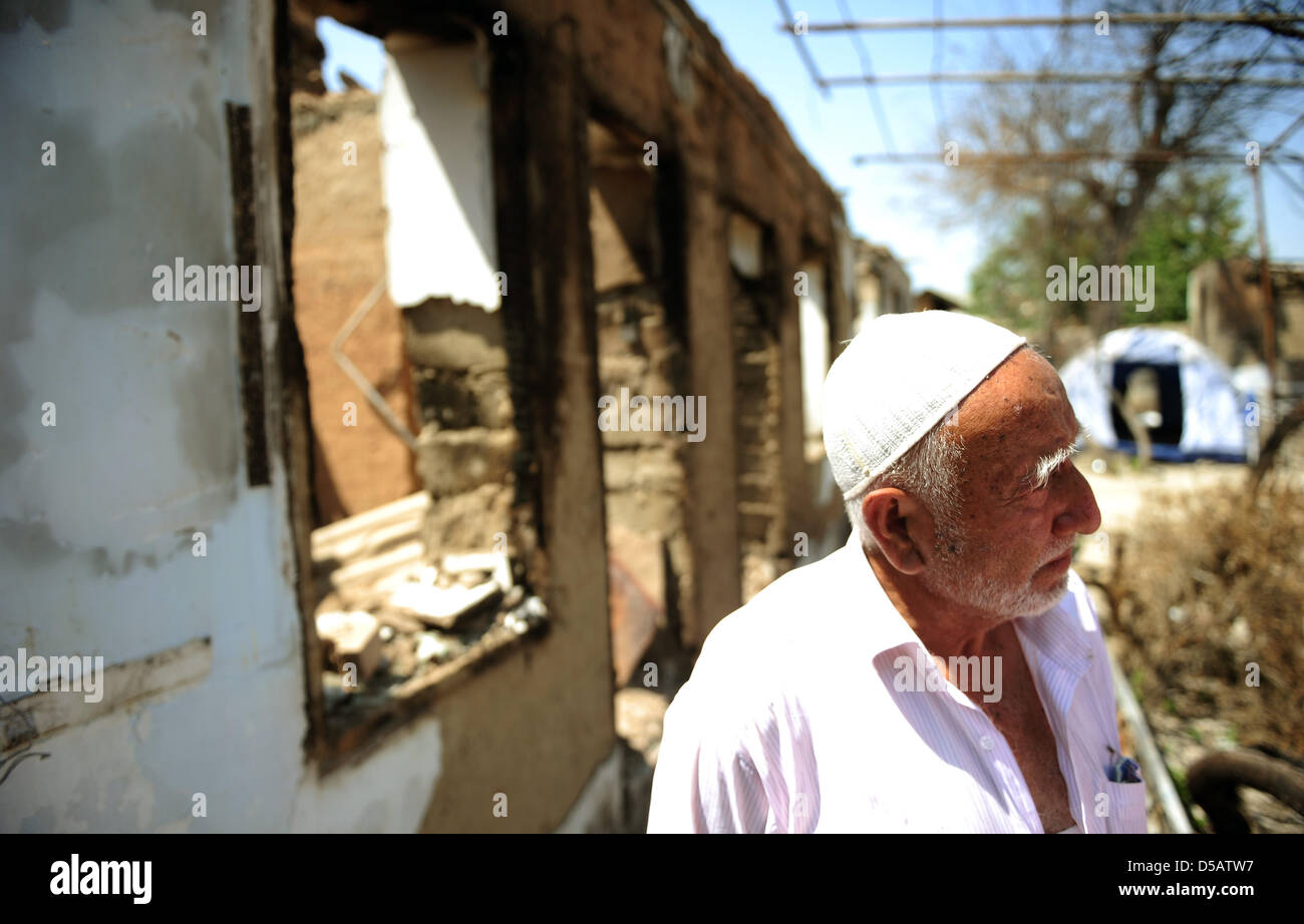 Ein Mann steht vor seinem beschädigten Grundstück in einer Wohngegend, die erschüttert hatte durch ethnische Störungen in Osch, Kirgisistan, 16. Juli 2010. Im Hintergrund kann ein Zelt entgegenkommend eine Familie gesehen. Westerwelle besucht Länder in Zentralasien. Foto: HANNIBAL HANSCHKE Stockfoto