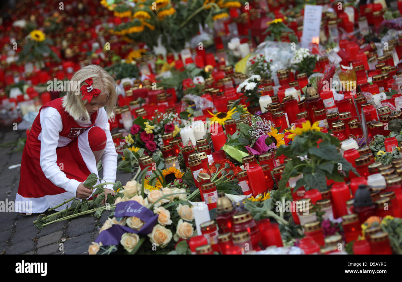 Kind Lisa legt Blumen auf dem Gelände der Loveparade in Duisburg, Deutschland, 28. Juli 2010. 21 Menschen starben und mindestens 340 Menschen wurden verletzt, während eine Massenpanik bei Techno-Musik-Festival Loveparade. Foto: Fredrik von Erichsen Stockfoto