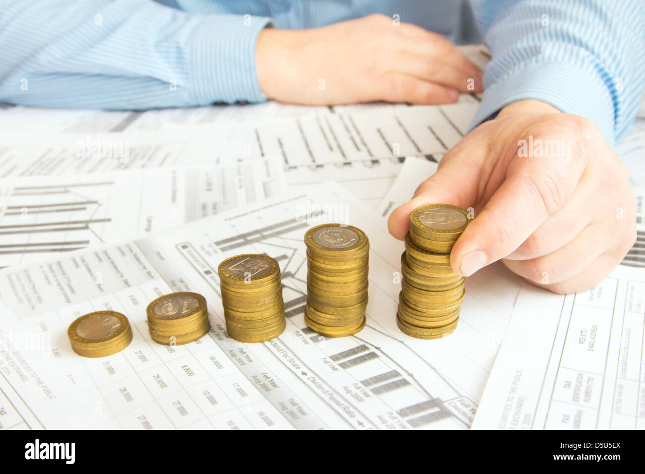 Stapel von Goldmünzen wie Spalten über verschiedene Dokumente Papierhintergrund erhöhen. Ergebnis oder rettende Diagramm (Diagramm). Stockfoto