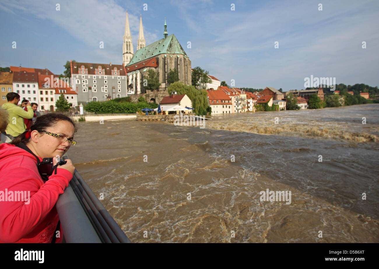 Zuschauer bestaunen die schnelle Wassermassen, die vorbei an der Kirche und der alten Stadt von der überschwemmten Stadt Görlitz in Deutschland, 8. August 2010 zu hetzen. Am Morgen wurde die Hochwassermarke lag bei 7,07 Meter - das höchste es die Protokollierung im Jahre 1912 begonnen. Hunderte von Menschen, die Leben in der Nähe des Flusses Neiße der vergangenen Nacht evakuiert werden mussten. Foto: Jan Woitas Stockfoto