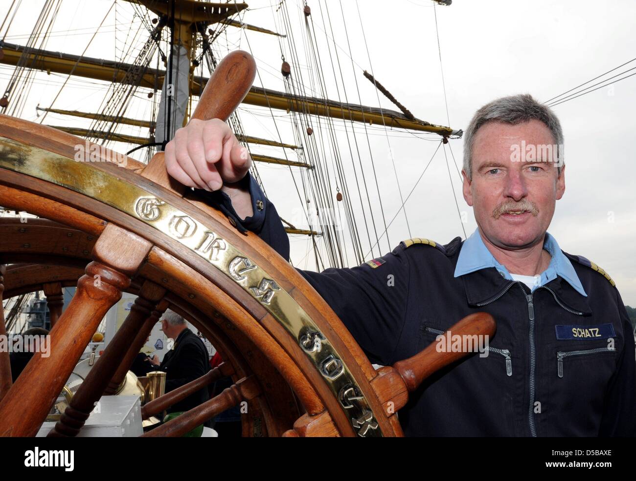 Captian Norbert Schatz des 3-Mast-Bark "Gorch Fock", Schulschiff der deutschen Marine, posiert mit dem Lenkrad als "Gorch Fock" den Marine Hafen von Kiel, Deutschland, 20. August 2010 geht. Die Ausbildung-Kreuzfahrt nach Südamerika soll Kap Hoorn zu umsegeln und decken mehr als 42.000 Kilometer die Mittel, um eine der längsten in der Geschichte. Mehr Stockfoto