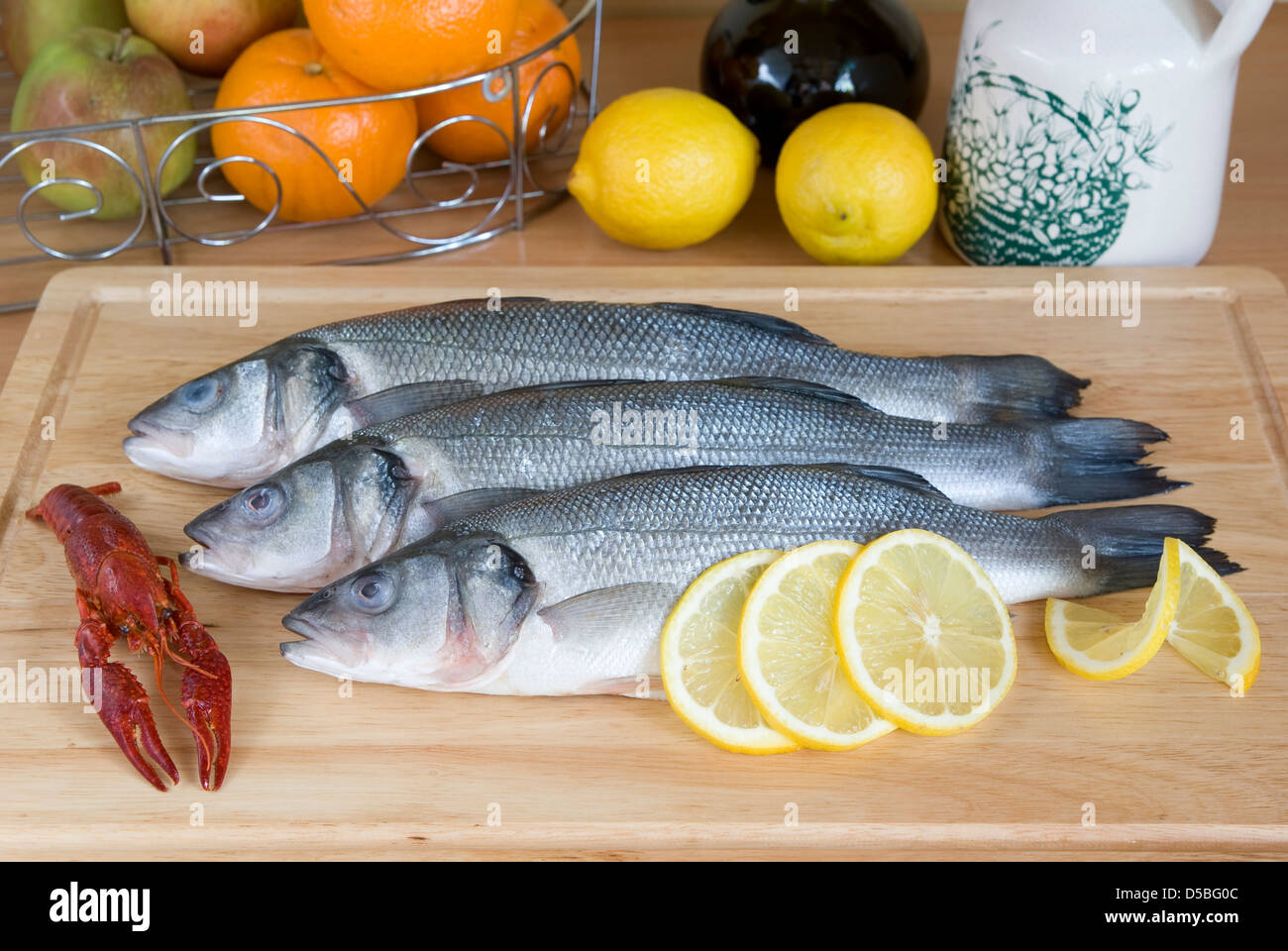 frischer Fisch und Zitronenscheiben auf Planke Stockfoto