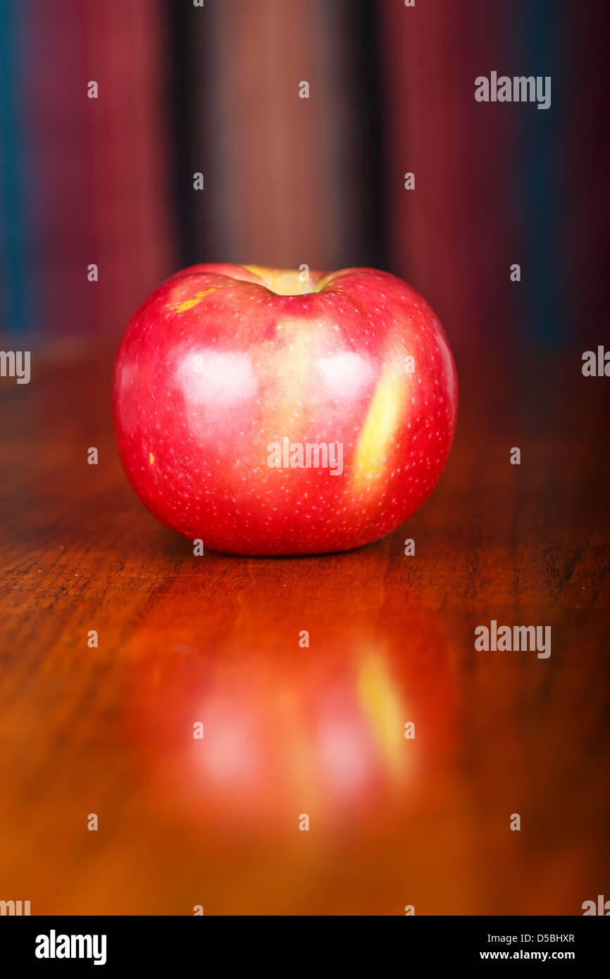 Einen einzigen Macintosh Apfel auf einem Holztisch mit leichten Reflexion Stockfoto