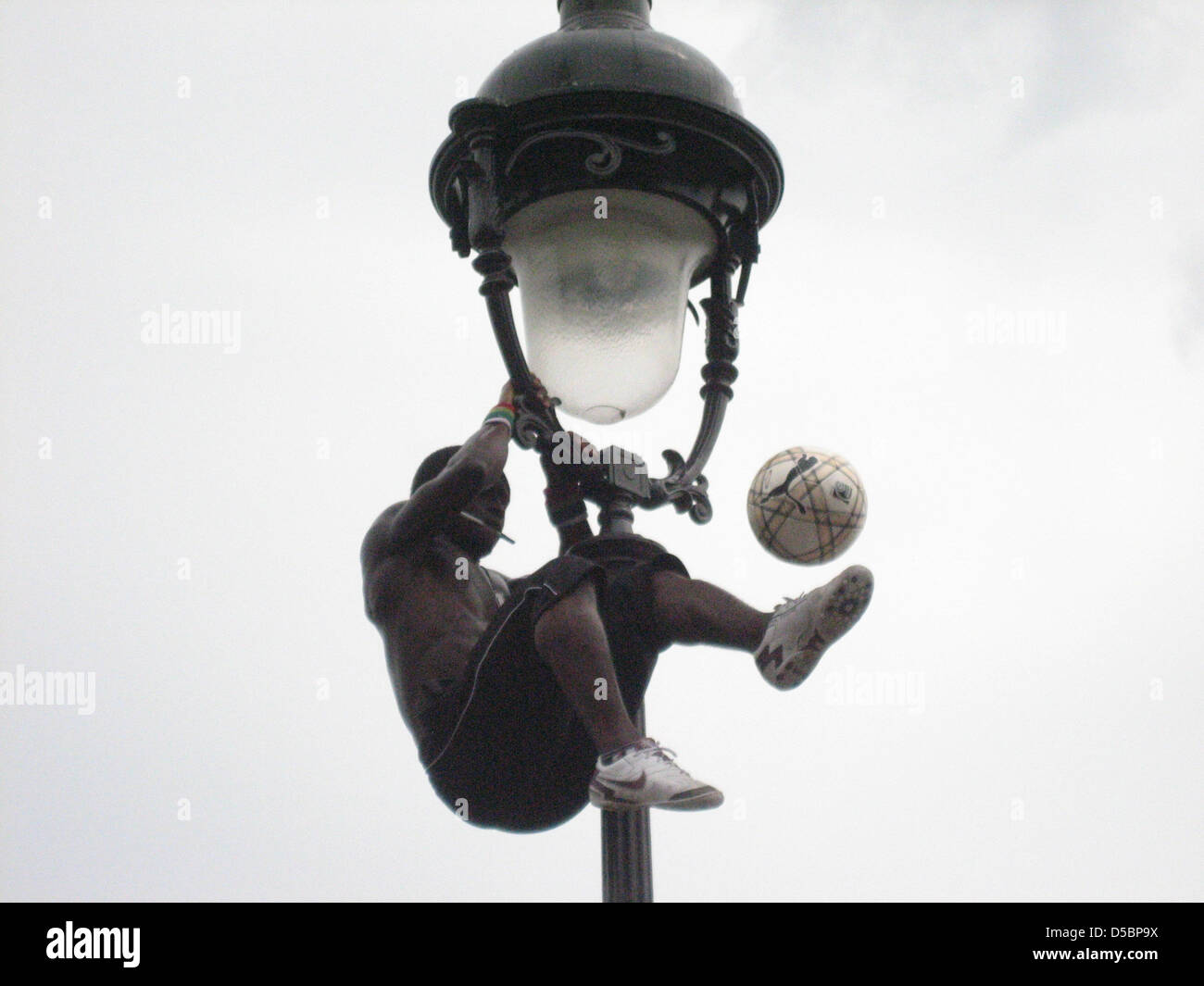 24-j hrige Iya Traore jongliert einen Fußball während baumelt an einer Straßenlaterne in Paris, Frankreich, 27. Juli 2010. Iya Traore ist eines der weltweit führenden Freestyle Fußball-Künstler. Foto: Nuria Wrobel Stockfoto