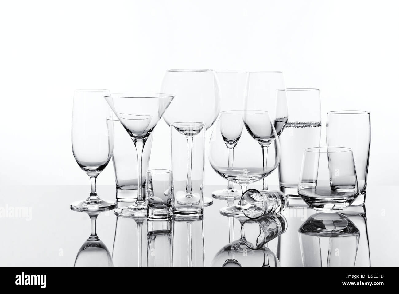 Vielzahl von 13 trinken Gläser, eins ist gefüllt, Hintergrundbeleuchtung Stockfoto