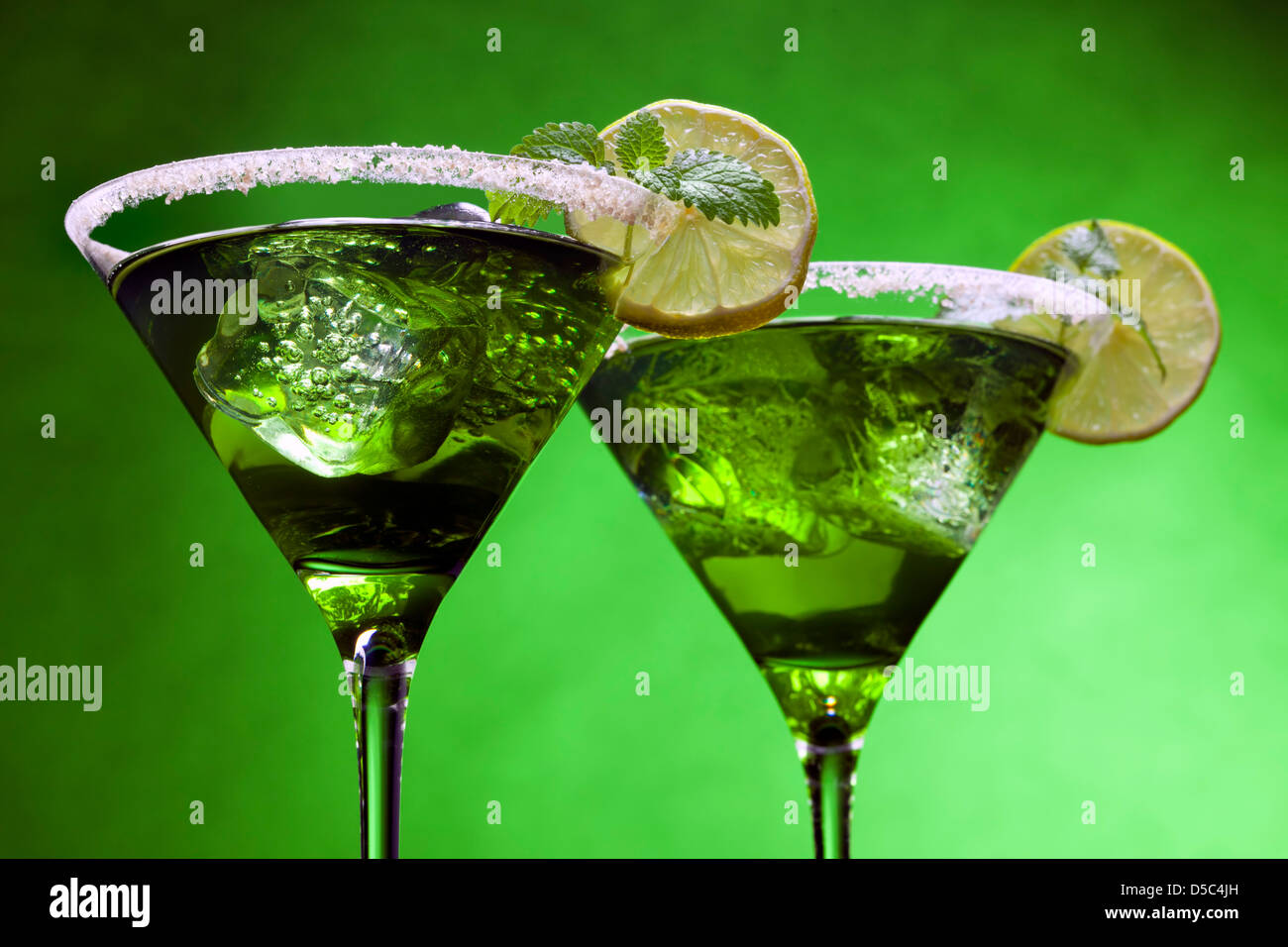 Grüne Cocktails in der Martini-Gläser mit gezuckerten Kanten, Limettenscheibe, Eiswürfel, Blatt Minze Stockfoto