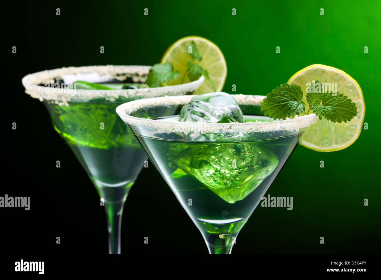 Grüne Cocktails in der Martini-Gläser mit gezuckerten Kanten, Limettenscheibe, Eiswürfel, Blatt Minze Stockfoto
