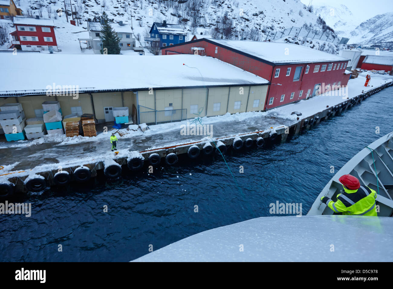 Hurtigruten Crew Mitglied wirft Schiffe Seil Hilfslinie Arbeiter Oksfjord während Winter Norwegen Europa andocken Stockfoto
