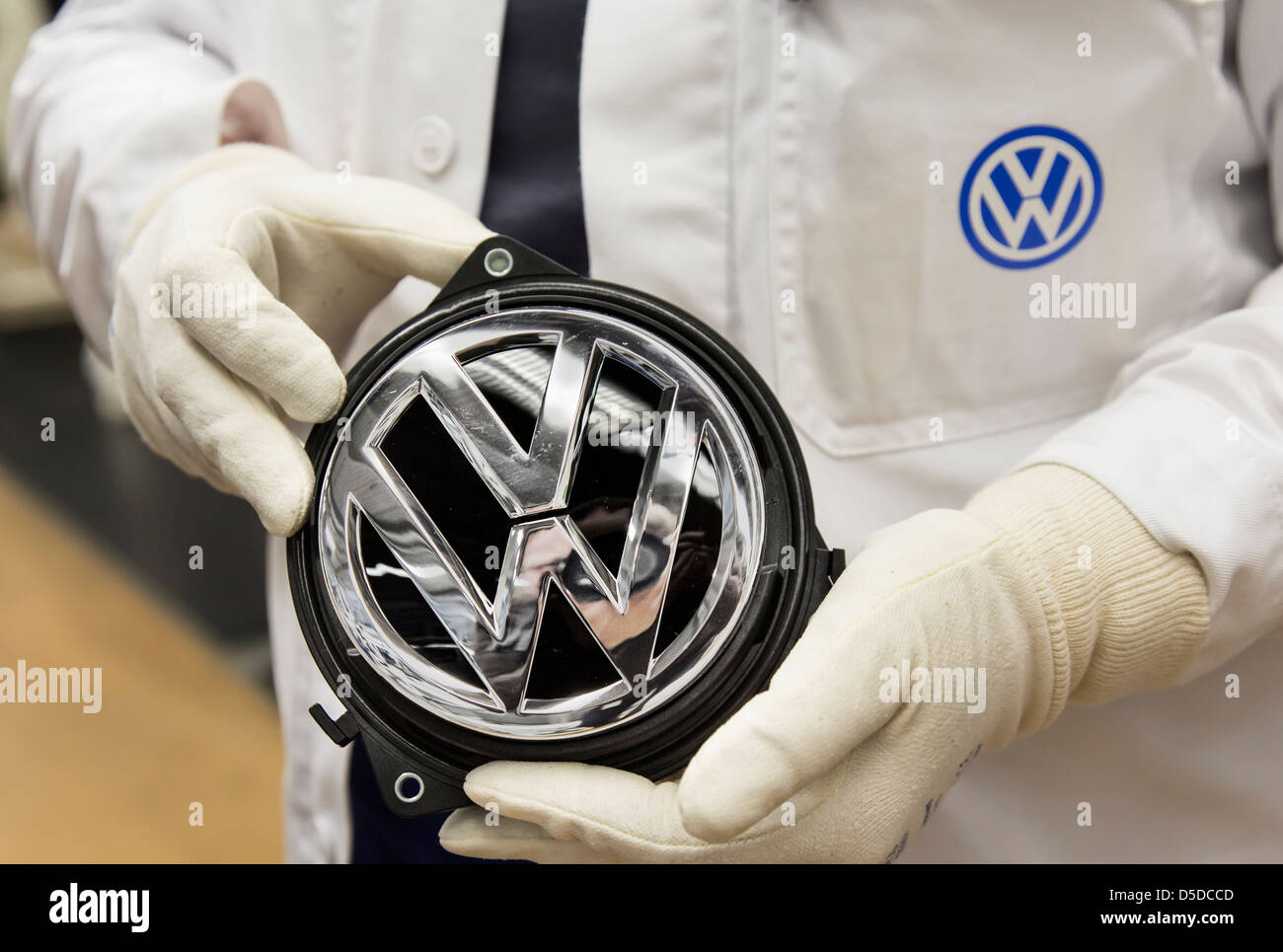 Arbeiter halten ein Volkswagen Logo bereit für die Endmontage in den Pkw-Werken der Volkswagen AG in Wolfsburg, Deutschland Stockfoto