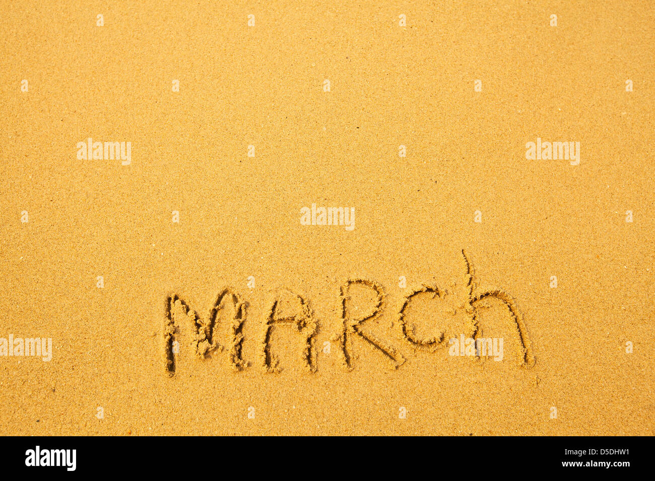 März - geschrieben im Sand am Strand Textur. Stockfoto