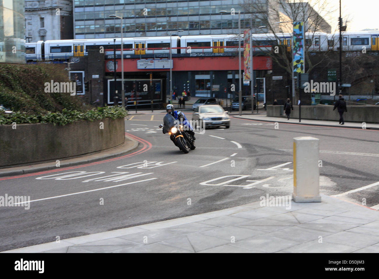 Ein Motorradfahrer und einem Auto unterwegs, um einen Kreisverkehr in der Nähe von Waterloo in London, England. Stockfoto