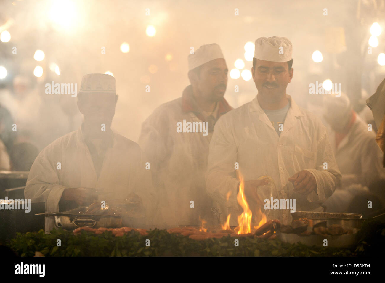 Männer kochen über einem rauchigen Feuer auf einem Wochenmarkt Stand in Djemaa al Fna Platz in Marrkesh, Marokko Stockfoto