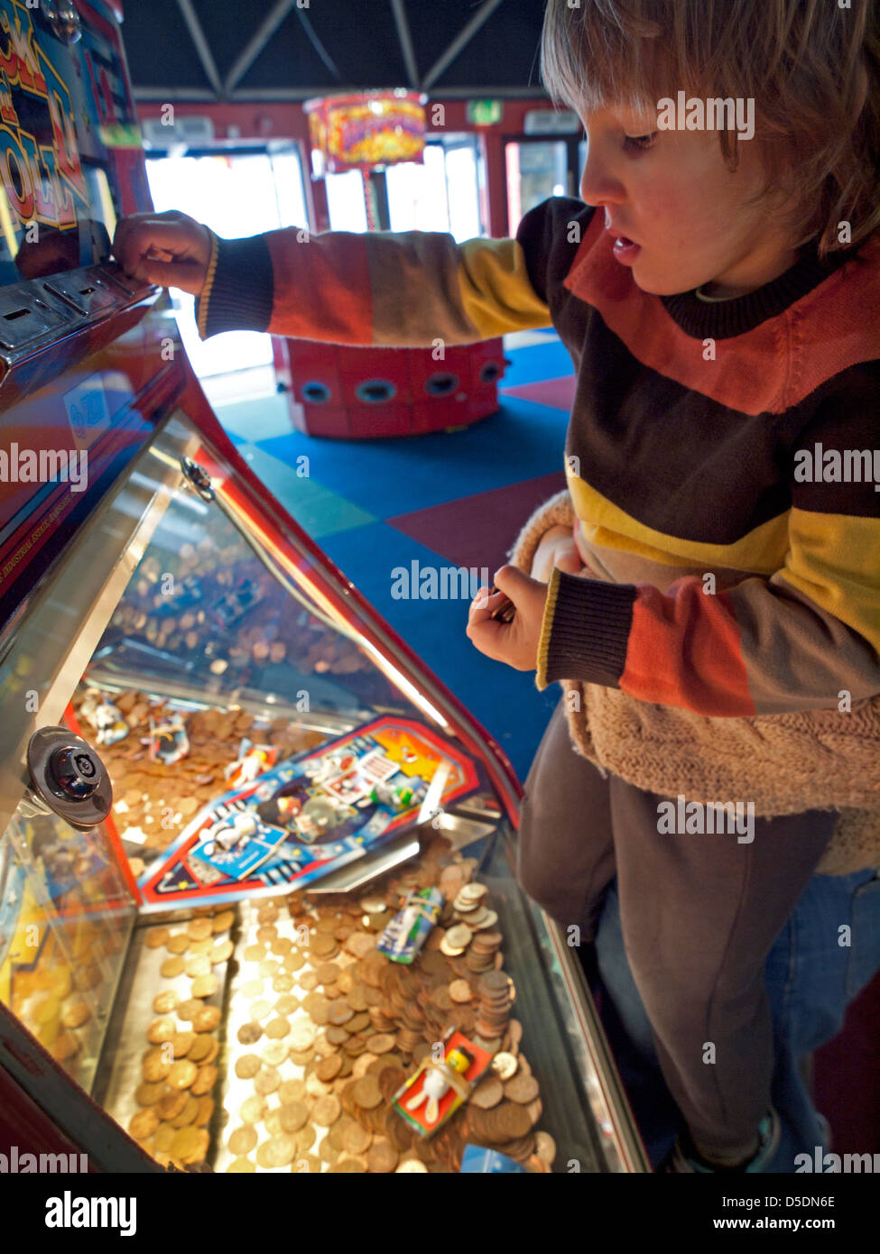 Ein kleiner Junge bringt Münzen in einen Slot Maschine auf Brighton Pier Stockfoto