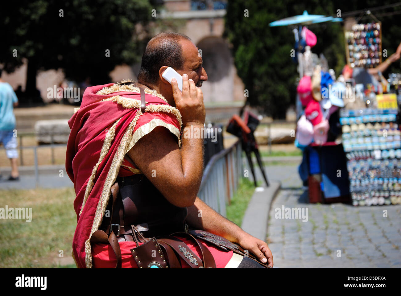 Ein Mann, gekleidet in eine antike römische Kostüm auf dem Handy vor dem Kolosseum Stockfoto